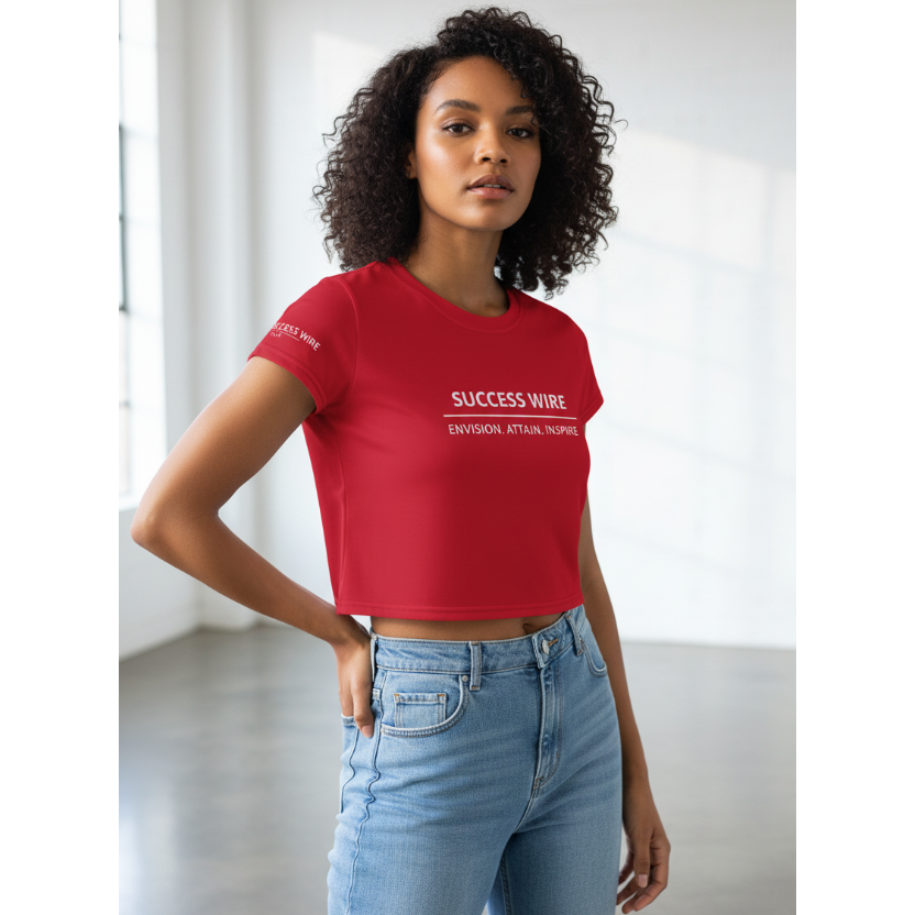 Woman wearing a red SUCCESS WIRE crop t-shirt with brand name and three pillars text and light blue jeans in a minimalistic setting
